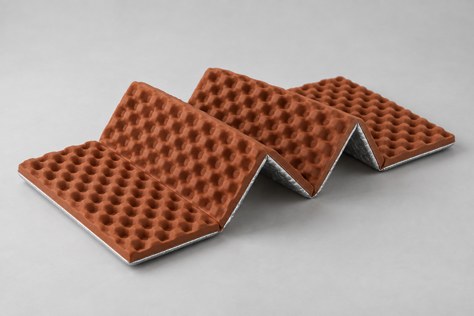 Illustrative brown folding foam sit pad with a textured surface and silver-colored backing